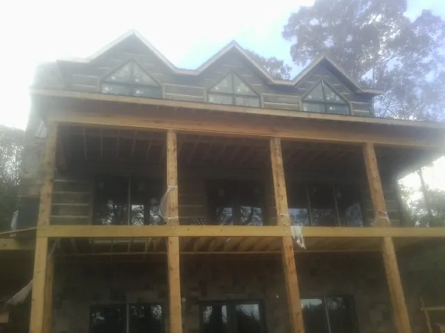 Dormers and porch framing on a large log home under construction — Roof Coating work by our crew in Prescott