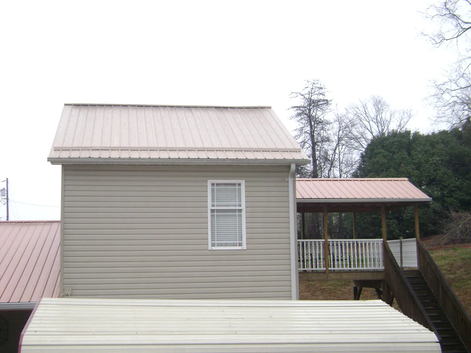 Tan metal roofs on a two story addition and attached porch, from a Roof Replacement job in Prescott