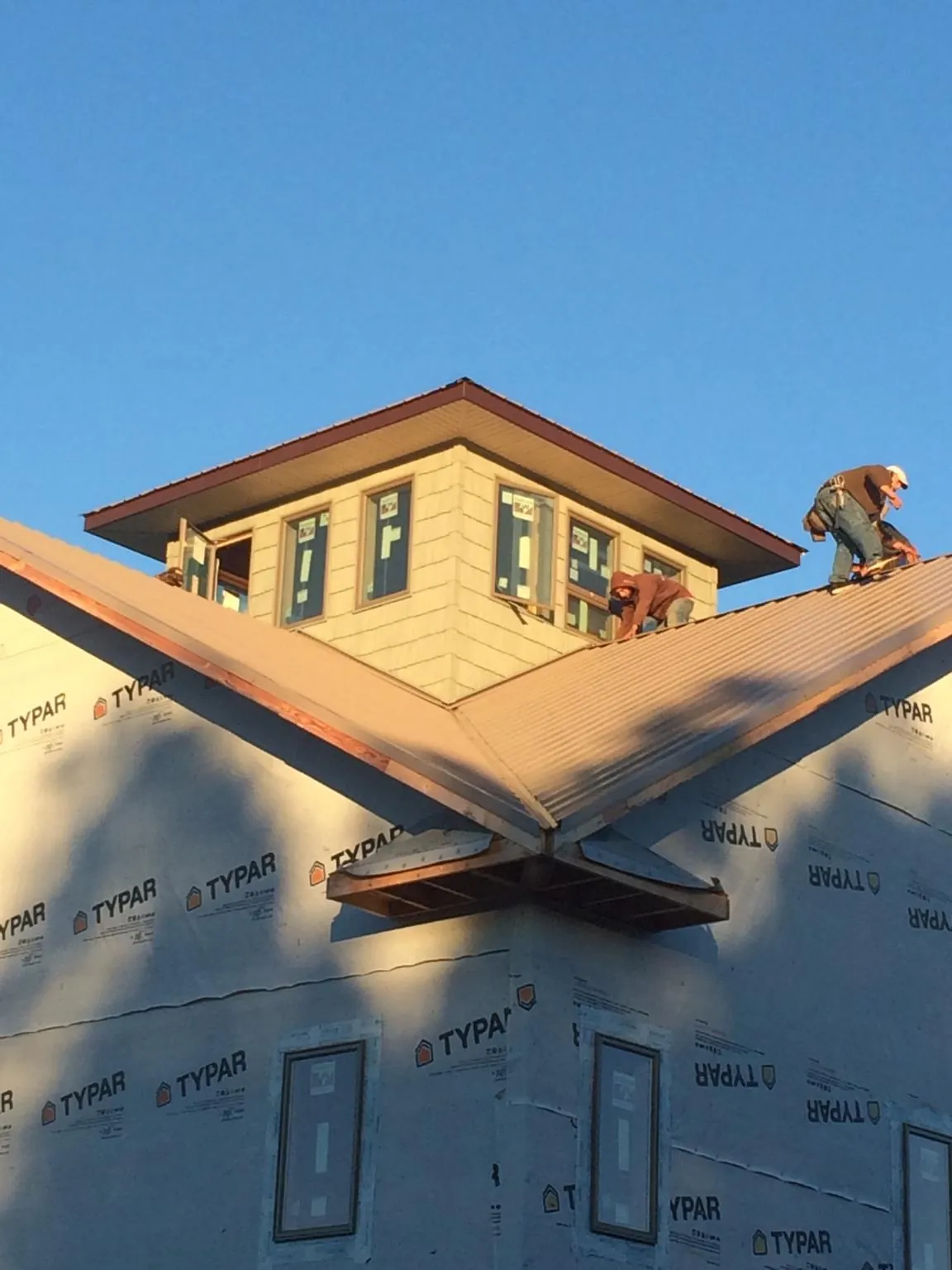 Roofers working around a rooftop cupola on a new metal roof at sunset — Roof Waterproofing in Prescott by Roofing Brothers